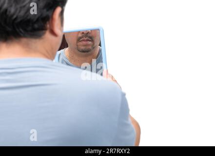 Uomo bearded che guarda nello specchio per le etichette della pelle o acrocordon sul collo isolato su sfondo bianco. Concetto di assistenza sanitaria Foto Stock