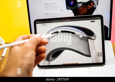 Parigi, Francia - 6 giugno 2023: Creative room table con pagina web di Apple su iPad Pro che mostra Apple Vision Pro Mixed Reality XR cuffie disegno mano maschile Foto Stock