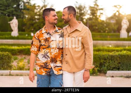 Romantico ritratto di sposi gay a piedi e divertirsi al tramonto in un parco della città. Diversità e concetto lgbt Foto Stock