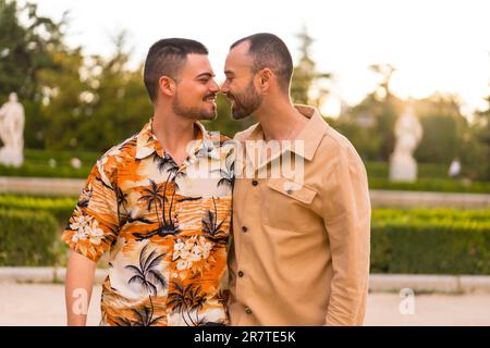 Romantico ritratto di sposi gay a piedi e divertirsi al tramonto in un parco della città. Diversità e concetto lgbt Foto Stock