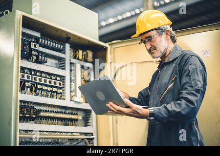 tecnico senior per la manutenzione del servizio di lavoro maschile manutenzione dell'armadio elettrico della macchina ad alta tensione Foto Stock