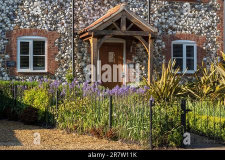 Tradizionale grazioso cottage in mattoni e selce con portico, giardino anteriore e percorso nel pittoresco villaggio di Great Massingham a Norfolk, Inghilterra Foto Stock
