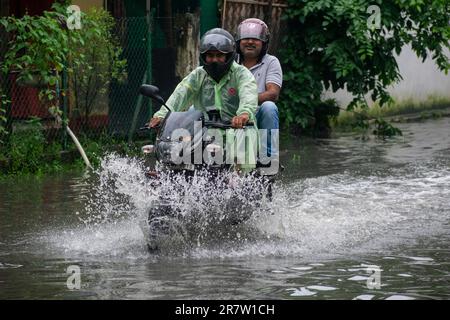 Il 14 giugno 2023, i pendolari svanirono in una strada allagata dopo forti piogge, a Guwahati, Assam, India. Il waterlogging è una scena comune nella città di Guwahati a causa del sistema di drenaggio povero. Credit: David Talukdar/Alamy Live News Foto Stock