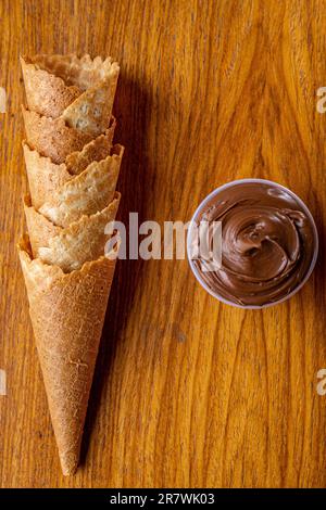 Un primo piano di coni di gelato con un tuffo su un tavolo di legno con un gelato vicino ad esso Foto Stock