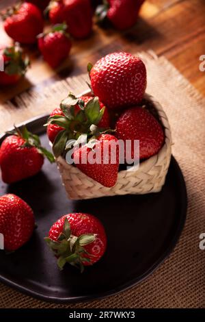 Fragole fresche biologiche (fragaria) su tavola di legno. Conosciuto anche come Frutilla in alcuni paesi di lingua spagnola, è un frutto di foresta che viene mangiato a. Foto Stock