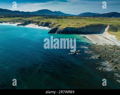 Una vista aerea di una splendida spiaggia con sabbia bianca finissima, un oceano blu cristallino e una lussureggiante erba verde su entrambi i lati Foto Stock