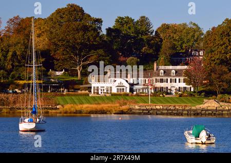 Una barca a vela e una piccola barca a motore fuoribordo sono ormeggiate al largo di una tenuta sul lungomare a Greenwich, Connecticut, una delle città più ricche d'America Foto Stock