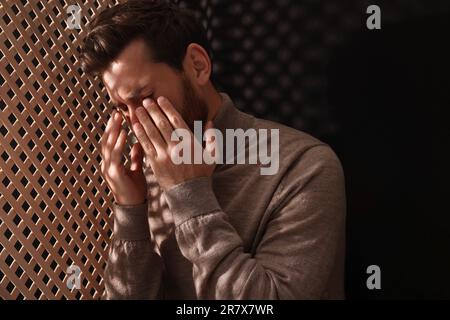 Sconvolgente l'uomo che ascolta il sacerdote durante la confessione in cabina, spazio per il testo Foto Stock