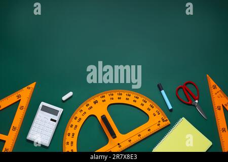 Composizione piatta con goniometro, triangolo e cancelleria su lavagna verde. Spazio per il testo Foto Stock
