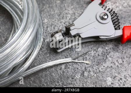 Taglierine e cavo con filo spelato su tavolo testurizzato grigio chiaro, primo piano Foto Stock