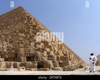 Un membro delle forze di sicurezza egiziane è di guardia alla base della grande Piramide di Giza fuori il Cairo, in Egitto. Foto Stock