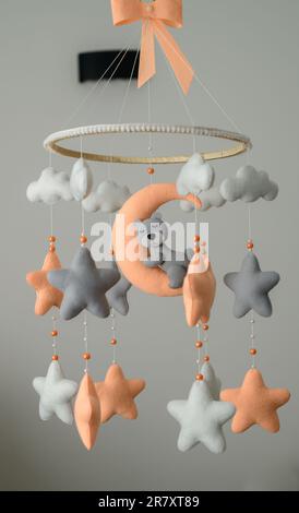 Culla mobile appesa nella stanza dei bambini, tema color pastello arancione e grigio, orso che dorme sulla luna circondato da stelle. Foto Stock