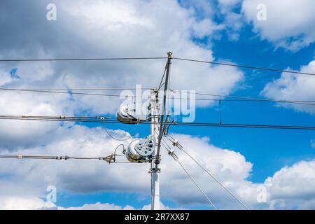 Pali di trazione della linea ferroviaria contro il cielo blu. Struttura in acciaio. Infrastrutture ferroviarie. Foto Stock
