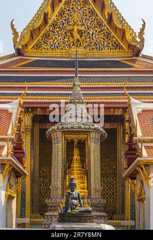 Il famoso tempio buddista Wat Phra Kaew, situato nel Grand Palace nel centro storico di Bangkok. In primo piano, la statua del seduto Foto Stock