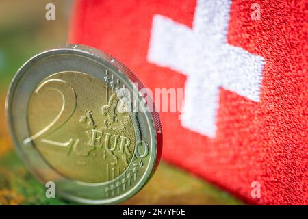 Moneta da 2 euro sullo sfondo della bandiera svizzera, concetto, cooperazione commerciale, tra l'area dell'euro e la svizzera, Relazioni commerciali del Foto Stock