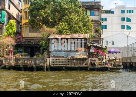 Case a palafitte lungo il fiume Chao Phraya nella megacity Bangkok. In molte parti, le case semplici sono state demolite e sono sostituite da Foto Stock