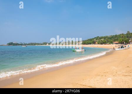 Sulla spiaggia di uno dei principali luoghi turistici nel sud-ovest dello Sri Lanka, Unawatuna vicino a Galle. I turisti possono prendere il sole, rilassarsi e fare acqua Foto Stock