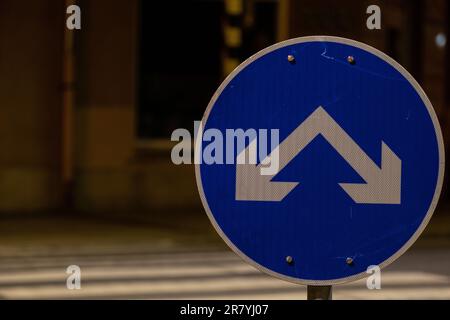 Un primo piano di un cartello stradale a doppia svolta con sfondo sfocato Foto Stock