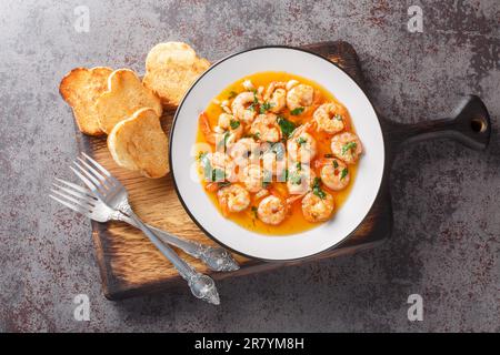 Gamberi all'aglio spagnolo con salsa ajillo sul piatto sul bordo di legno. Vista orizzontale dall'alto Foto Stock
