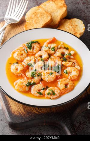 Gambas al Ajillo stile spagnolo aglio gamberi closeup sul piatto sul bordo di legno. Verticale Foto Stock