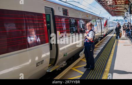 Grantham Train Station – Una direttrice o guardia femminile che spedisce un treno Azuma London North Eastern (LNER) dalla piattaforma Foto Stock