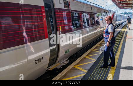 Grantham Train Station – Una direttrice o guardia femminile che spedisce un treno Azuma London North Eastern (LNER) dalla piattaforma Foto Stock