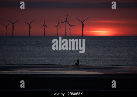 Tramonto sulle turbine eoliche offshore sulla costa settentrionale del Galles Foto Stock
