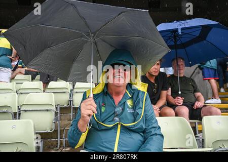 Un ventilatore australiano si ripara dalla pioggia sotto un ombrello mentre il gioco si ferma durante il LV= Insurance Ashes First Test Series Day 3 Inghilterra contro Australia a Edgbaston, Birmingham, Regno Unito, 18th giugno 2023 (Foto di Craig Thomas/News Images) Foto Stock