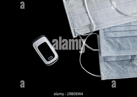 Digitale, baby infrarossi termometro febbre allarme pulsazioni pulsossimetro ossigeno sangue frequenza cardiaca monitoraggio oximetro nero con maschere mediche. Foto Stock