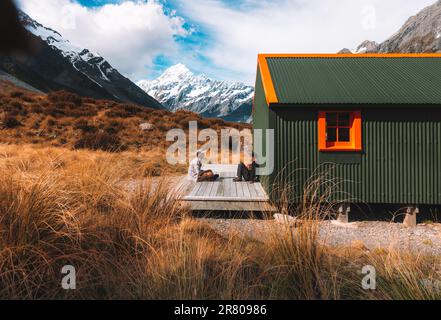 Due giovani turisti maschi di fronte all'Aoraki Mount Cook Hooker Hut. Ponte sospeso sul circuito Hooker Valley. Canterbury, Nuova Zelanda, Sud Foto Stock