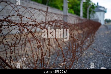 Oranienburg, Germania. 18th giugno, 2023. Il filo spinato arrugginito giace a terra contro un muro sul terreno dell'ex campo di concentramento di Sachsenhausen. Nel giugno del 1938, gli agenti di polizia criminali hanno deportato più di 10.000 persone nei campi di concentramento, dove sono state segnate con un angolo nero. La campagna di arresto a livello nazionale è stata diretta contro persone che sono state etichettate 'asocial? Dai socialisti nazionali. Tra di loro c'erano senzatetto, alcolisti e persone con un record criminale per, tra l'altro, l'elemosina. Credit: Monika Skolimowska/dpa/Alamy Live News Foto Stock