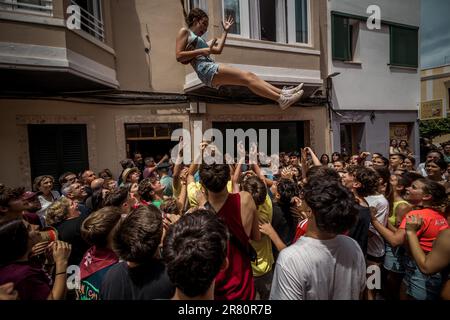 Ciutadella, Spagna. 18th giugno, 2023. Una ragazza viene gettato in aria mentre un giovane uomo rivestito in una pelle di pecora, l''Homo des Be' (uomo di pecora), portando un ariete vivo intorno alle sue spalle la Domenica prima che il festival di San Giovanni di Ciutadella visita la casa di un 'caixer' (cavaliere) Credit: Matthias Oesterle/Alamy Live News Foto Stock