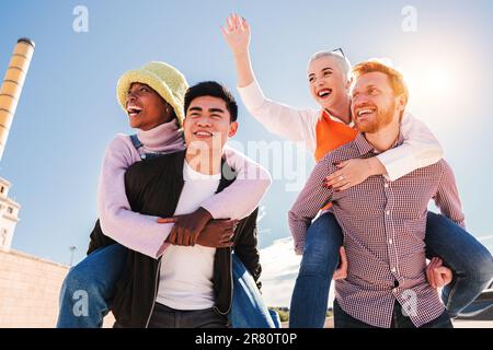 Coppie felici che si divertono durante un fine settimana di attività. Due maschi che danno un giro di piggyback alle sue donne. Giovani eccitati che ridono e sorridono insieme. Coppia di fidanzati che portano le sue fidanzate. Foto di alta qualità Foto Stock