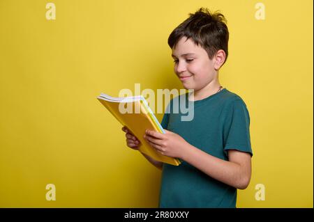 Adorabile ragazzo con libri, isolato su sfondo giallo. Spazio di copia. Istruzione. Erudizione. Ritorno a scuola Foto Stock