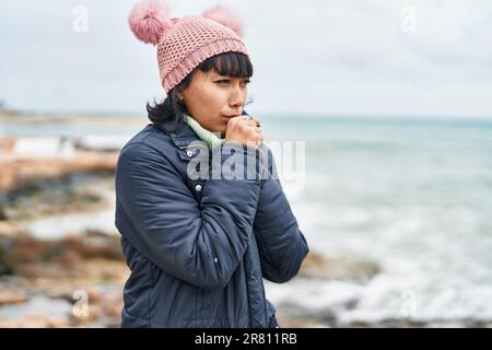 Giovane bella donna ispanica tosse al mare Foto Stock