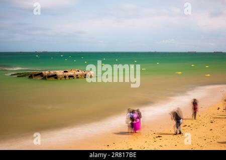 Turisti che scattano foto di fronte ai resti di un porto di Mulberry WW2, Arromanches-les-Bains, Normandia, Francia Foto Stock