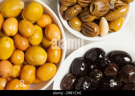 un set di tre tipi di olive in ciotole bianche - olive verdi grandi intere Foto Stock