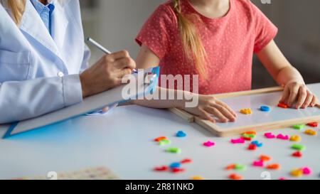 Bambina che fa le parole dalle lettere di plastica colorate durante l'incontro con lo psicologo Foto Stock