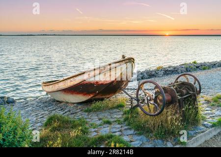 Barca a remi su scivolo con meccanismo di sollevamento lungo la diga Del Ijsselmeer con le nuvole di pioggia di colore rosso che scivola sopra il lago Foto Stock