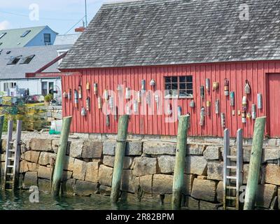 Le boe d'ormeggio sono appese al tabellone rosso e al muro di listelli del punto di riferimento Motif numero uno della baracca da pesca sul Bradley Wharf a Rockport, Massachusetts Foto Stock