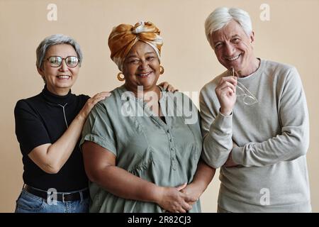 Un gruppo eterogeneo di persone anziane che si pongono insieme e sorridono alla macchina fotografica Foto Stock
