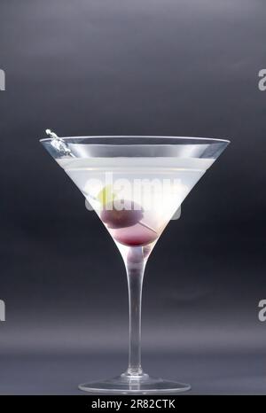 Twist allettante: Martini con il delizioso Cherry Garnish ruba lo spettacolo con la selezione di fenicotteri su un lato di vetro isolato su sfondo nero Foto Stock