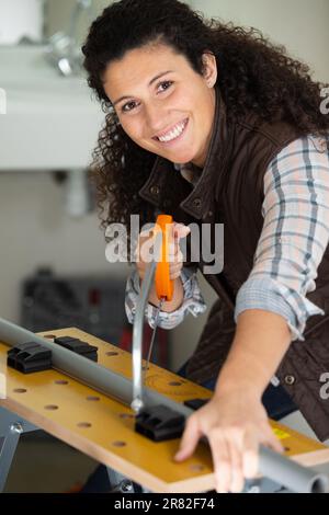 una donna felice che usa un hacksaw Foto Stock