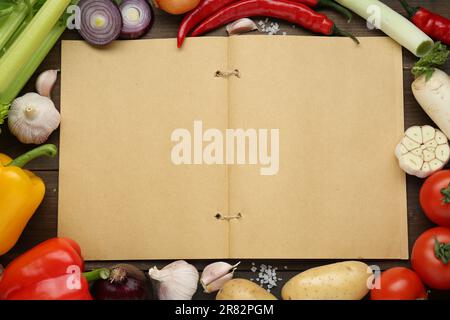 Libro di ricette in bianco circondato da diversi ingredienti su tavolo di legno, piatto. Spazio per il testo Foto Stock