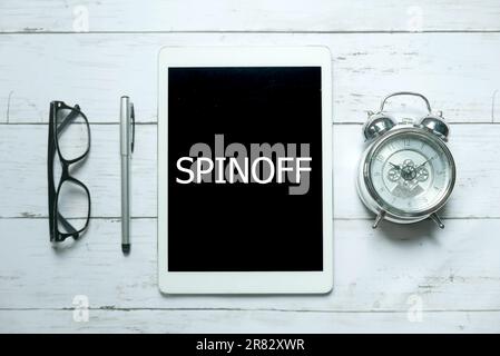 Business Concept.Top vista di occhiali, orologio, penna e tablet scritto con Spinoff su sfondo di legno bianco. Foto Stock