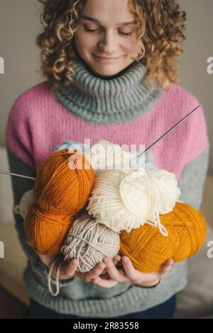 Vista ravvicinata di una donna impegnata nel lavoro ad ago che tiene in mano matasse di filato multicolore per i suoi prodotti. Artigianato e creatività. Fatto a mano Foto Stock