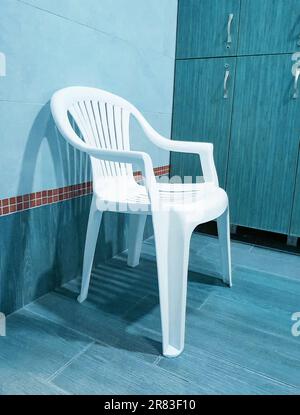 Una sedia di plastica bianca si trova vicino agli armadietti di legno nello spogliatoio del club sportivo, verticale Foto Stock