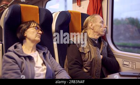 Una coppia anziana viaggia in treno, un anziano guarda fuori dalla finestra, una donna che dorme Foto Stock