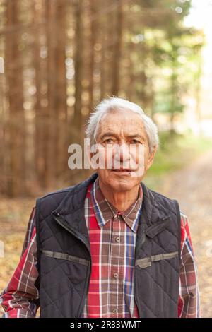 Ritratto di un uomo anziano in una camicia a quadri nella foresta autunnale Foto Stock