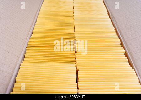 Primo piano di una scatola di cartone rettangolare riempita con due pile di buste imbottite gialle ordinatamente confezionate all'interno. Foto Stock